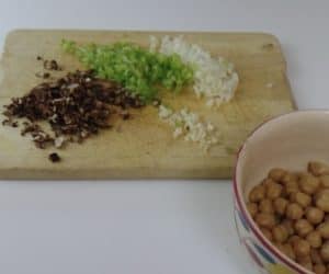 chopped onion, garlic, peppers, mushrooms on a board with a bowl of chickpeas